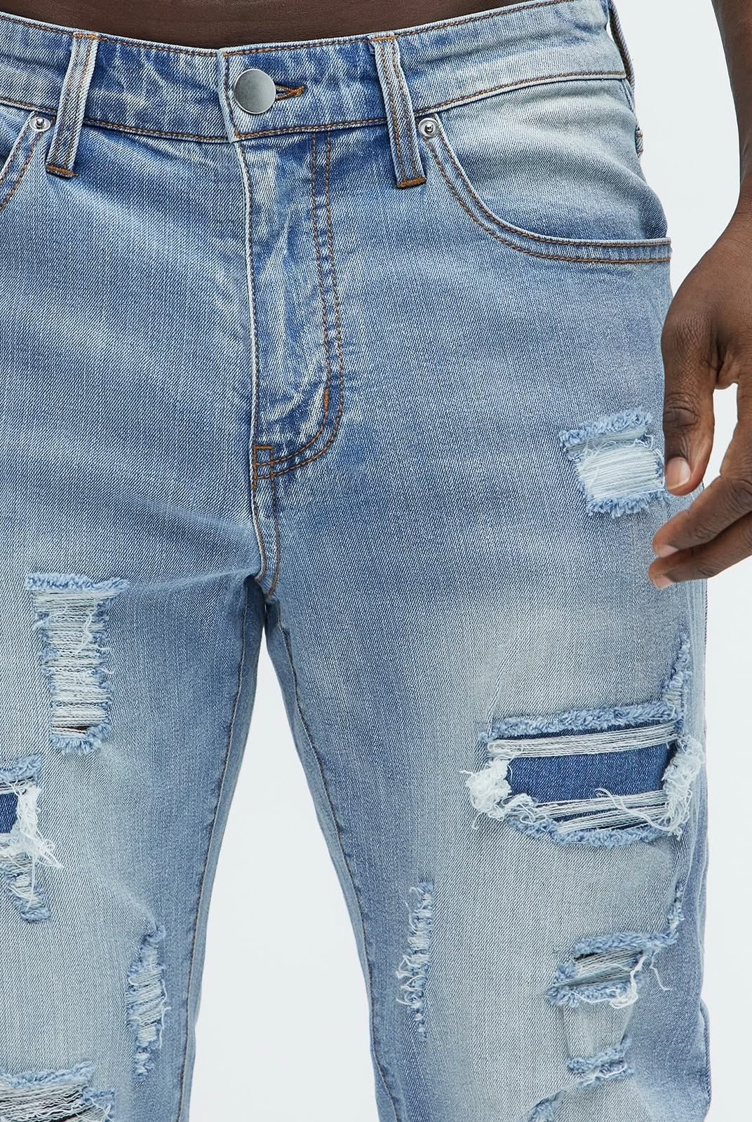 Detalle frontal del jeans Fashion Nova azul claro rasgado con parches para hombre