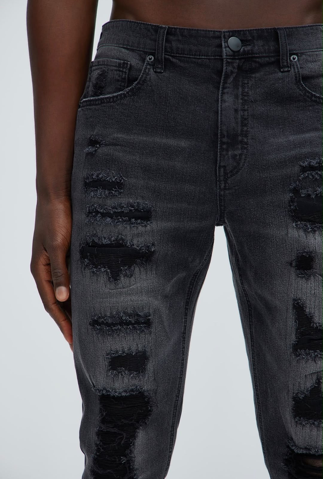 Detalle del desgaste frontal del jeans Fashion Nova negro para hombre